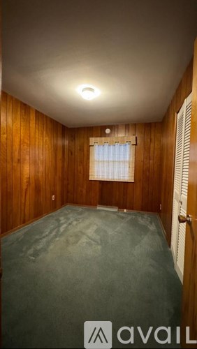 A room with wooden walls and a window with blinds.