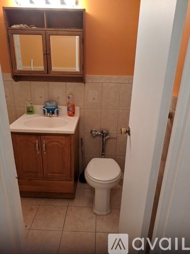 A bathroom with a toilet, sink, and wooden cabinet.