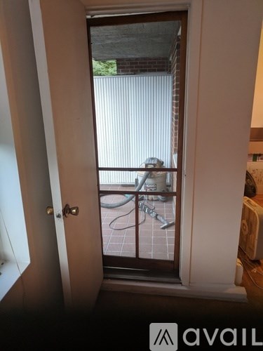 A room with a door and a window with a view of a balcony.