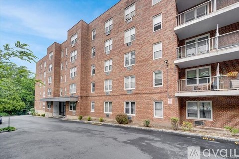 A large brick apartment building with a parking lot in front.