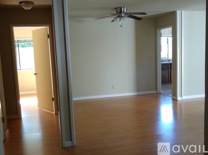 A spacious room with a ceiling fan and wooden flooring.