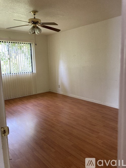 A room with a ceiling fan and wooden flooring.