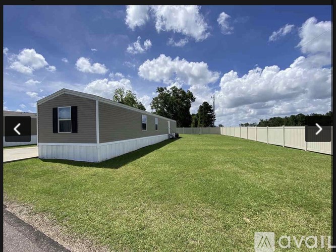 A small house with a grey roof and a white fence in front of it.