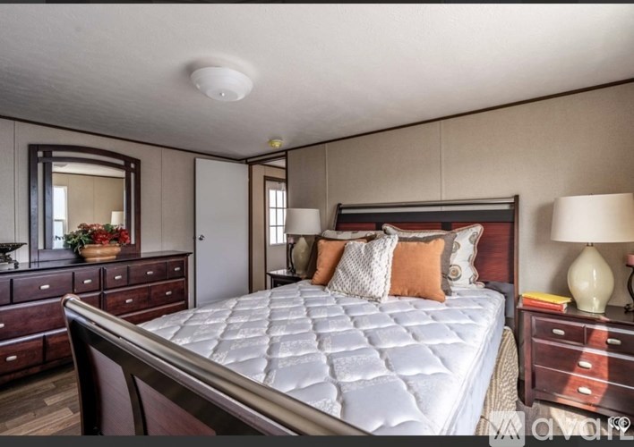 A bedroom with a large bed, a dresser, and a mirror.