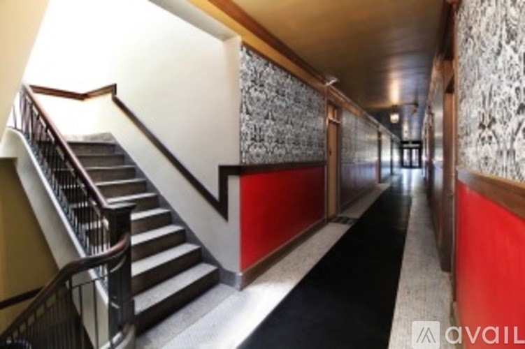 A hallway with a staircase on the left and a wallpapered wall on the right.