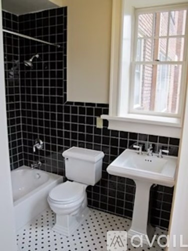 A white toilet and sink in a black and white tiled bathroom.