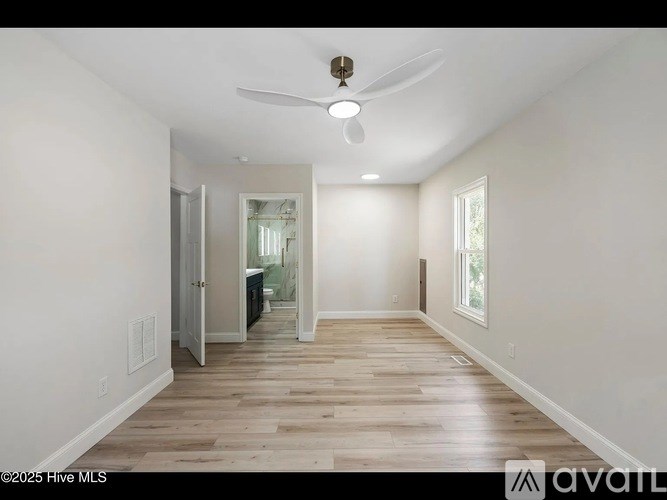 A spacious room with wooden flooring and a ceiling fan.