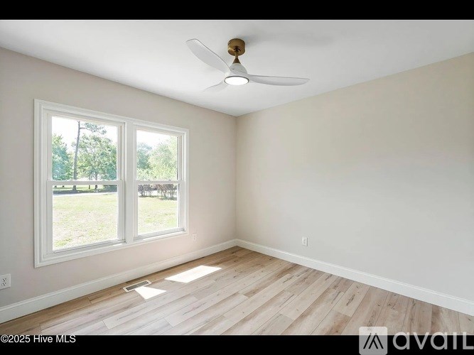 A room with a ceiling fan and two windows.