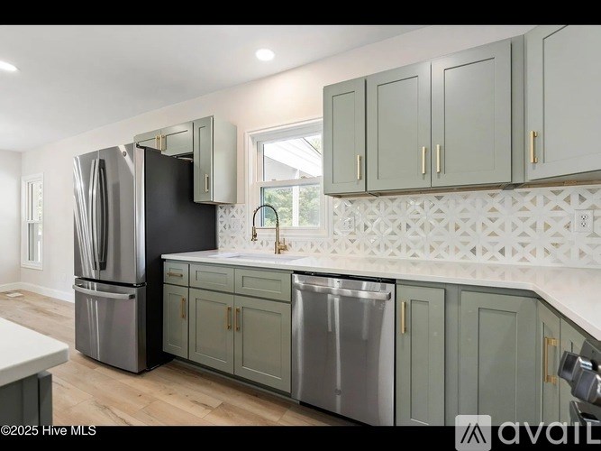 A kitchen with a black refrigerator and grey cabinets.