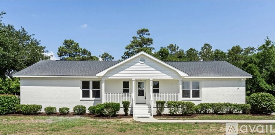 A white house with a black roof and a porch.