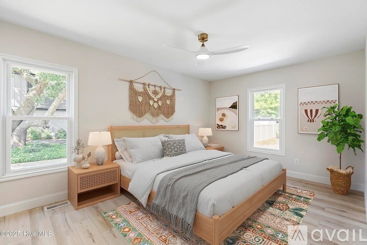A bedroom with a bed, a window, a plant, and pictures on the wall.