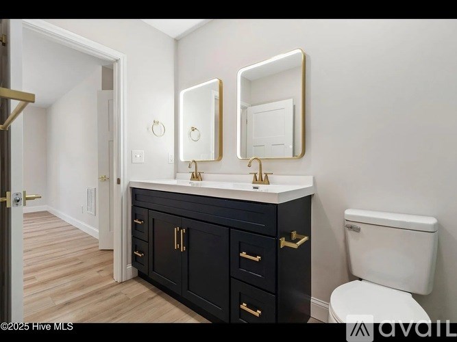 A bathroom with a white toilet, a sink with a gold faucet and a mirror above it.