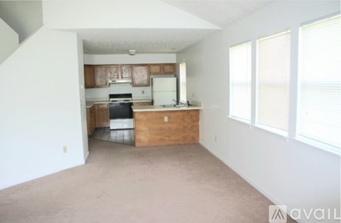 A kitchen with a stove, sink, and cabinets is in the background.