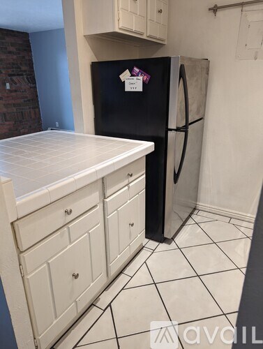 A kitchen with a black fridge and white cabinets.