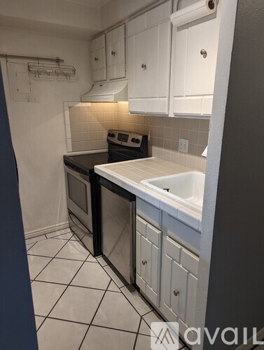 A kitchen with white cabinets and a black dishwasher.