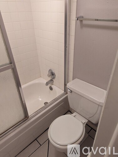 A white toilet sits next to a bathtub in a bathroom.