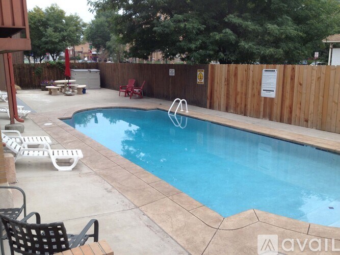 A pool with a blue tinted water and a wooden fence around it.