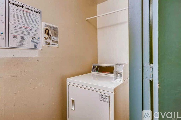 A white washing machine is in a small room with a sign on the wall.