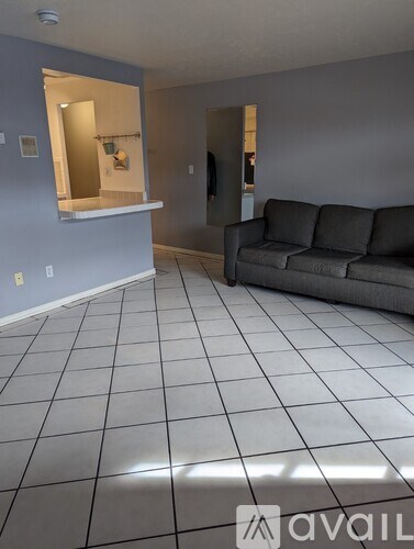 A living room with a grey couch and a tiled floor.