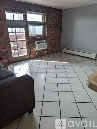 A living room with a grey couch and a brick wall.