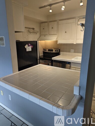 A kitchen with a black fridge and white cabinets.