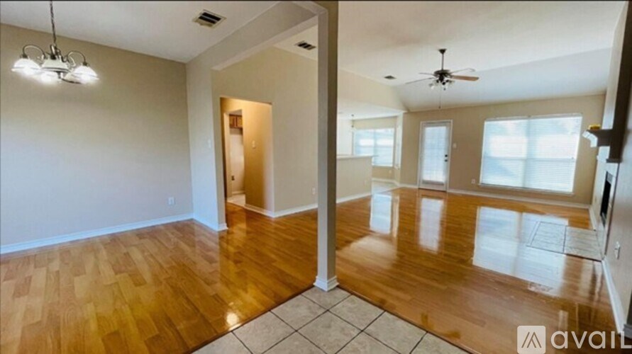 A spacious room with wooden flooring and a ceiling fan.