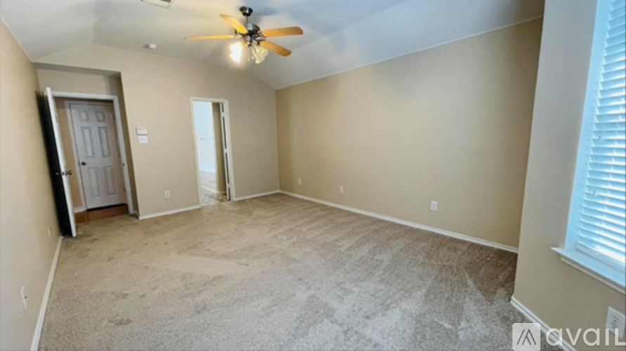 A spacious room with a ceiling fan and carpeted floor.