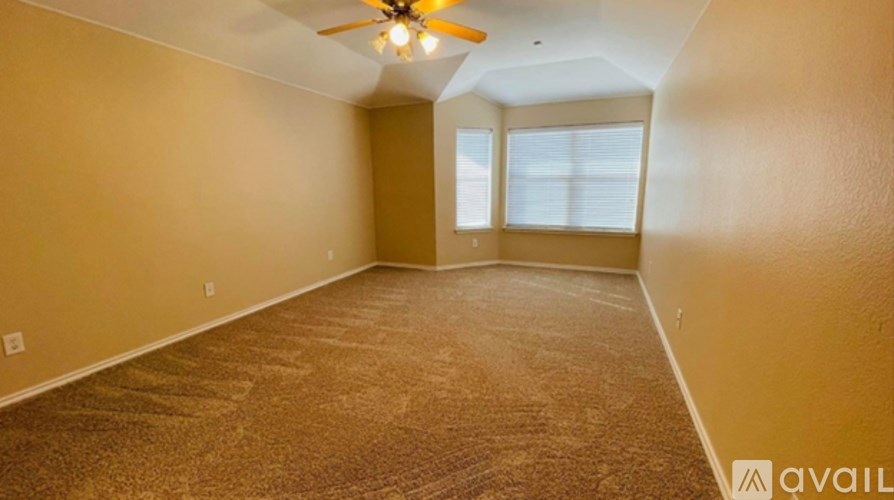 A room with a carpeted floor and a ceiling fan.