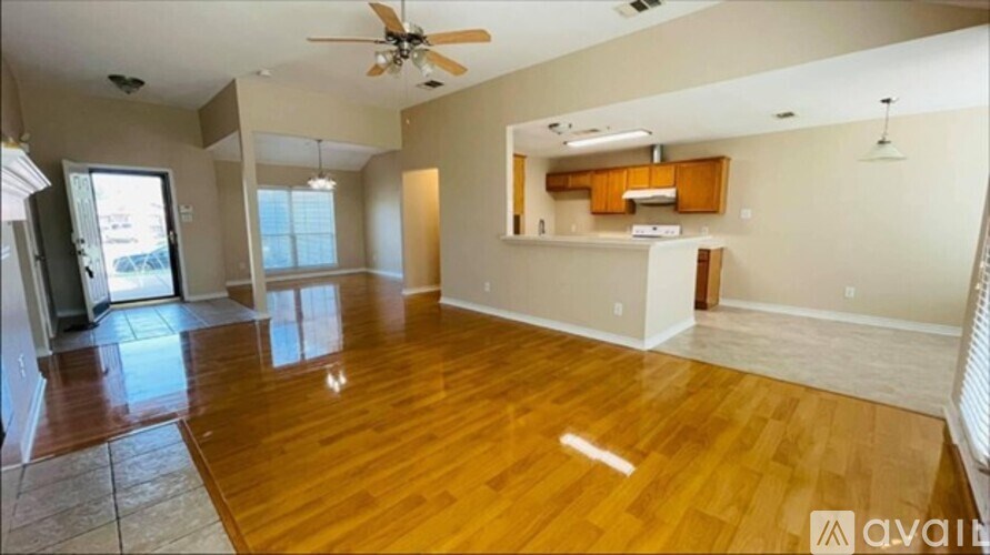 A spacious living room with hardwood floors and a ceiling fan.