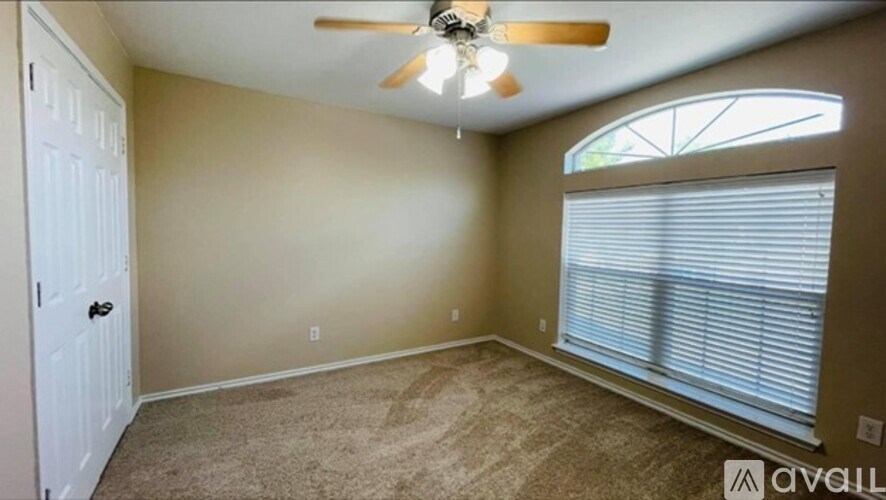 A room with a ceiling fan and a window with blinds.