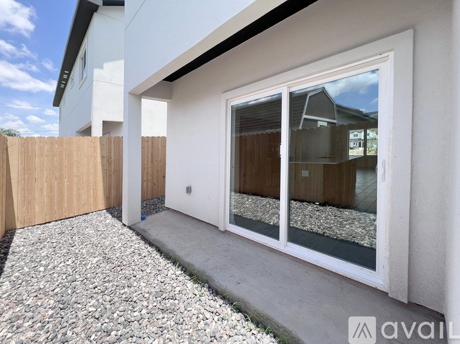 A white house with a gravel path leading to a white door with a glass window.
