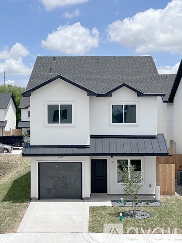A white house with a black roof and a black garage door.