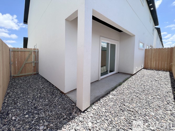 A white house with a gravel driveway and a wooden fence.