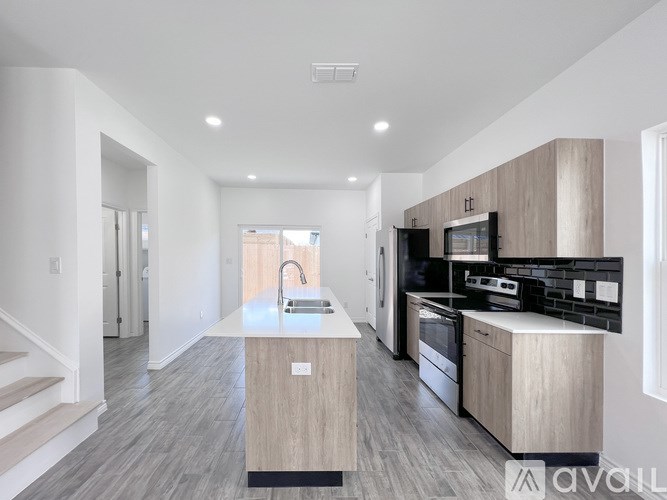 A modern kitchen with a sink, stove, and refrigerator.