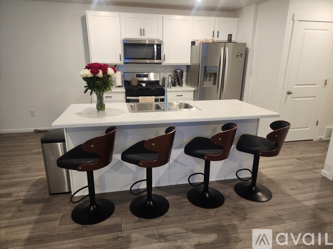 A kitchen with a white island and four bar stools.