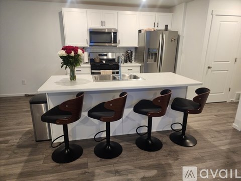 A kitchen with a white island and four bar stools.