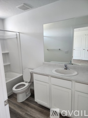 A bathroom with a toilet, sink, and mirror.