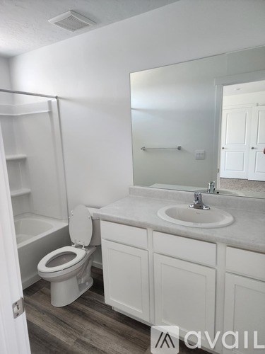 A bathroom with a toilet, sink, and mirror.