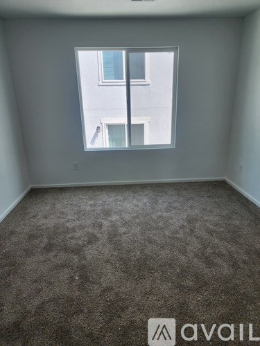 A carpeted room with a window overlooking a building.