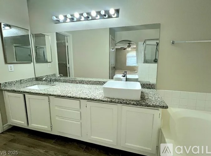 A bathroom with a granite countertop and white cabinets.