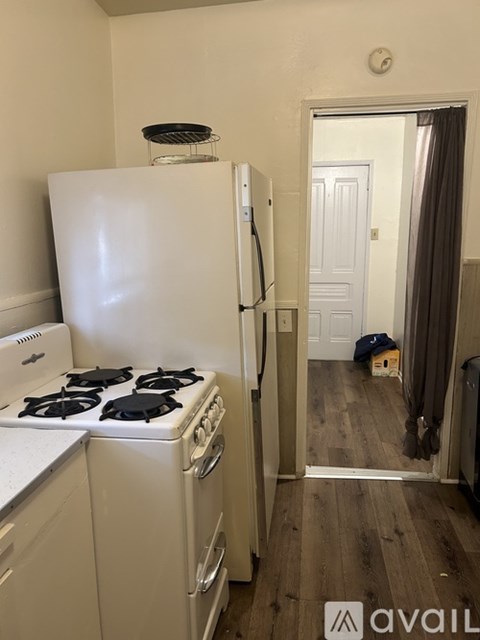 A white fridge and stove in a kitchen with a mirror in the hallway.
