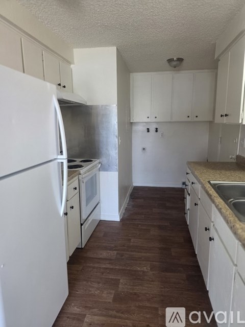 A kitchen with white cabinets and a white fridge.