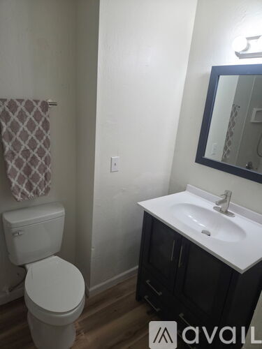 A bathroom with a toilet, sink, and mirror.