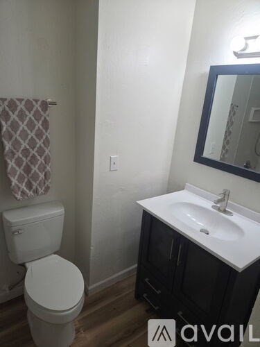 A bathroom with a toilet, sink, and mirror.