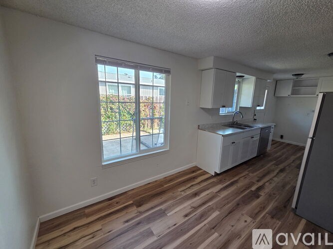 A room with wooden flooring and a window overlooking a balcony.