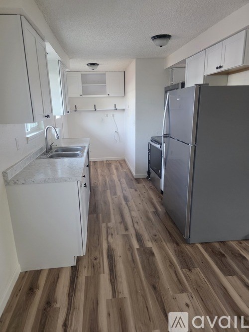A kitchen with a sink, refrigerator, and cabinets.