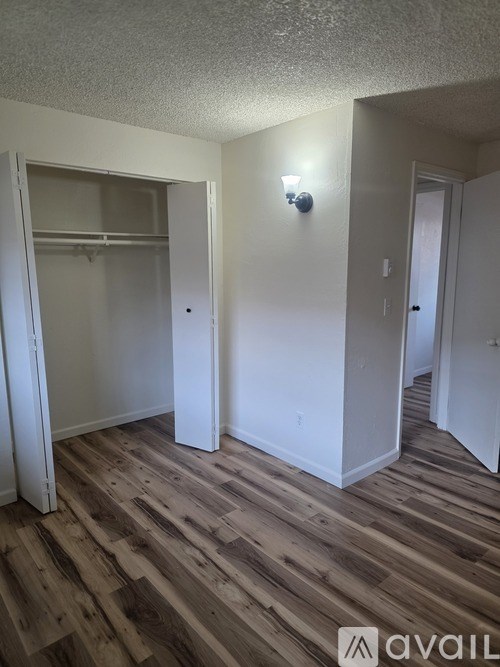 A room with a wooden floor and a white wall with a light switch.