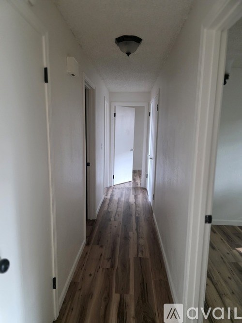 A long hallway with wood floors and white walls.