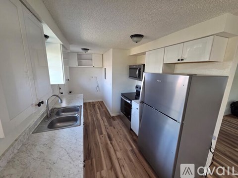 A kitchen with a refrigerator, sink, and cabinets.