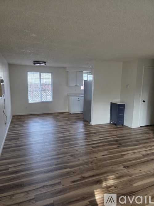 A room with wooden flooring and a window with blinds.